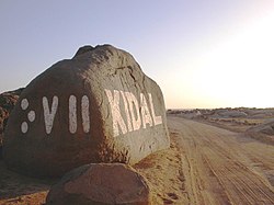 Entrée de Kidal. Sur le côté gauche du roché, Kidal est écrit en caractère tifinagh (écriture berbère des touaregs) : " kd'l ".