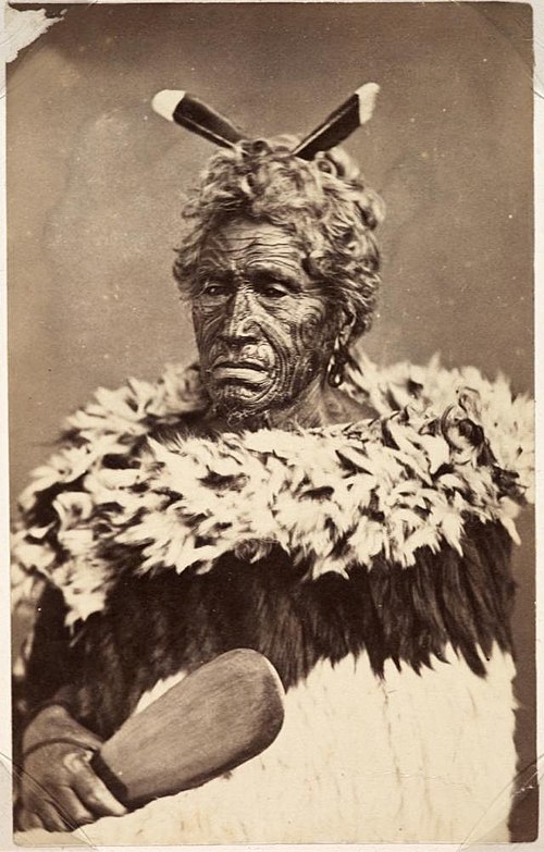 Traditional formal dress of the Classic/contact period, including a dog-skin cloak (kahu kuri), and a mere or patu (short edged weapon).