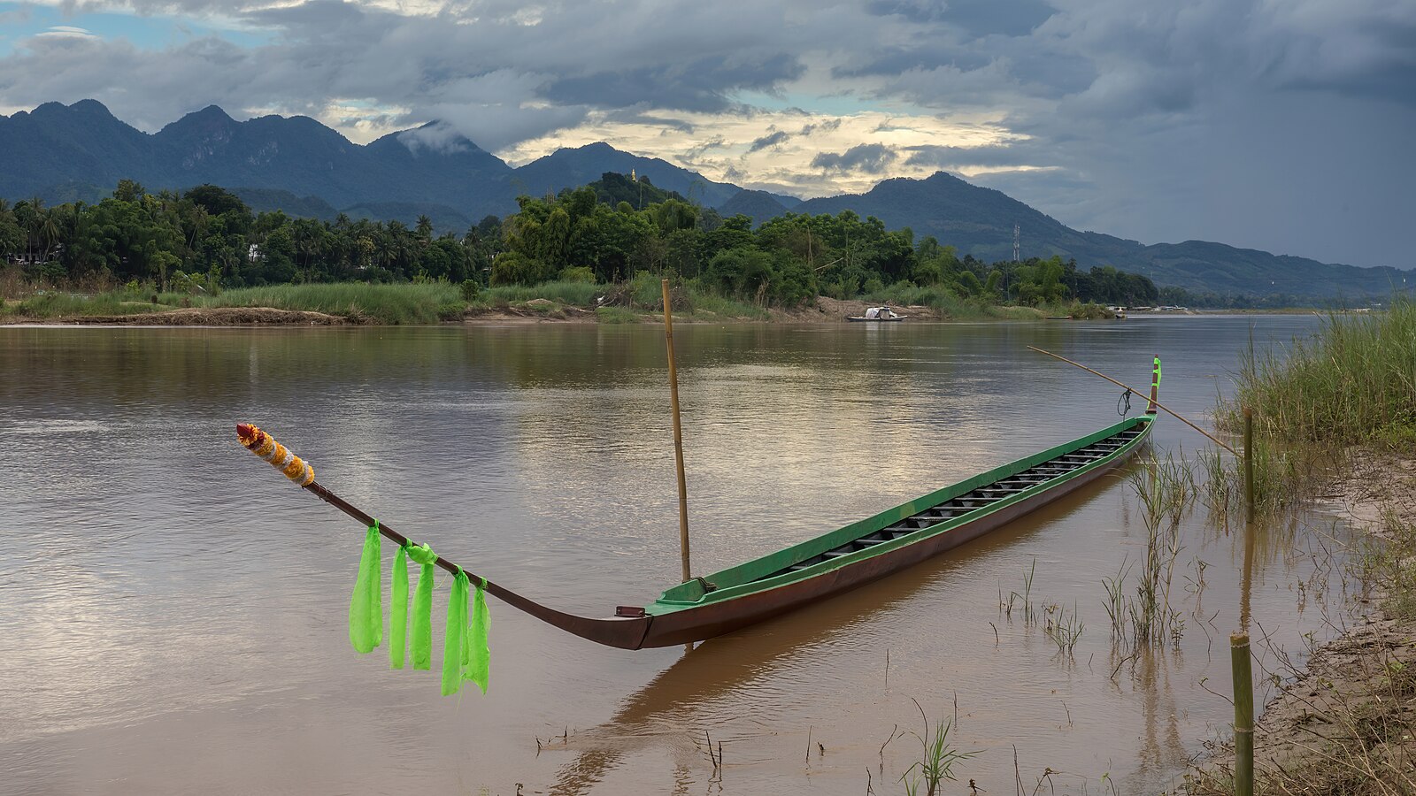 Pirogue with decorative green ribbons moored to the Mekong bank in Luang Prabang Laos