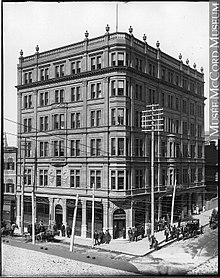 Photo extérieure en noir et blanc d'un immeuble en briques de six étages à l'architecture victorienne, vers 1895