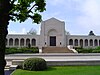 A two-story white marble chapel set on a small hill at an American military cemetery in France, with rounded arch entryway and colonnades to the right and left