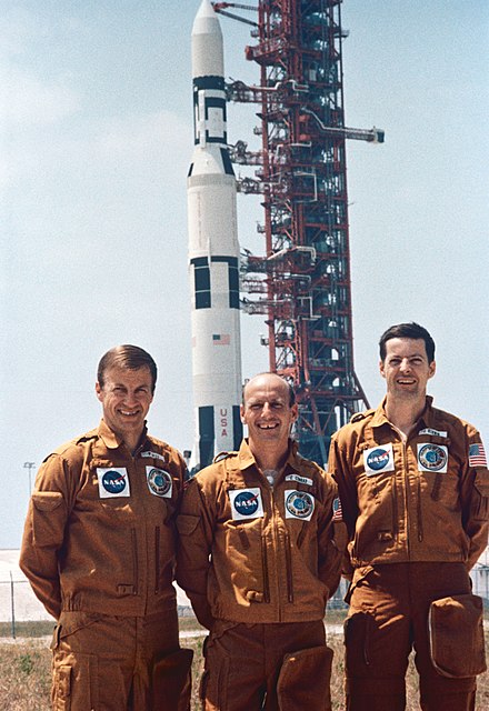 Paul J. Weitz, (left) Charles Conrad Jr. (middle); and Joseph P. Kerwin (right); in front of Skylab station on its Saturn V