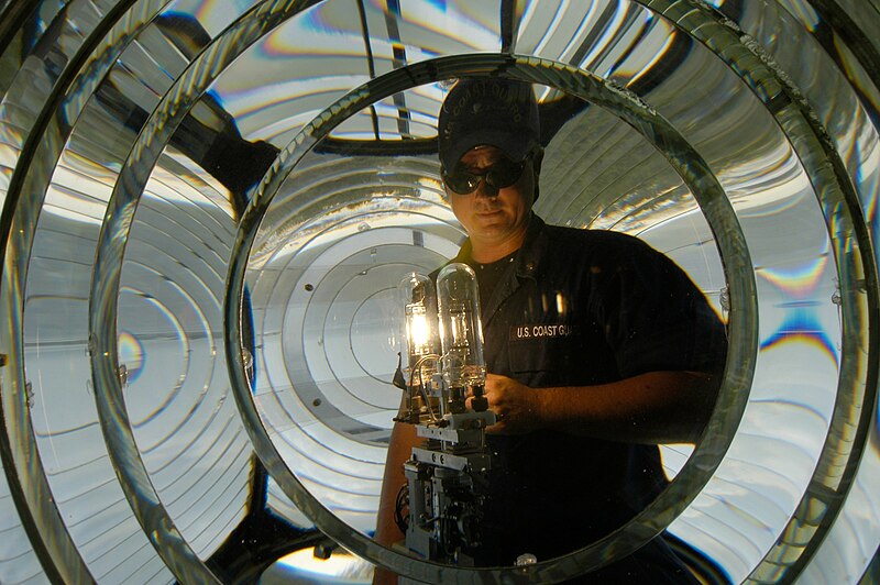 File:US Navy 040813-N-5328N-004 Electrician's Mate 3rd Class Ryan Pritchard looks through the center of a fresnel lens while testing a new lamp to ensure it is working properly, at the lighthouse on board Naval Air Station (NAS) Pensacola.jpg