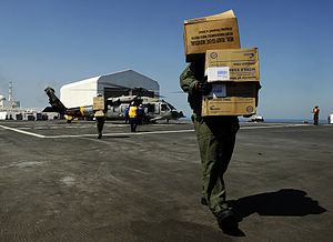 US Navy 100202-N-5345W-095 crewmen and flight deck personnel unload medical relief supplies from an MH-60S Sea Hawk helicopter.jpg