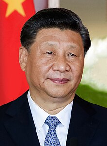 Head shot of Xi Jinping in 2019. He is wearing a black suit jacket, white shirt and a blue necktie.