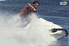 Photo d'Ayrton Senna, torse nu, aux manettes d'un jet-ski blanc, de profil, sur les vagues.