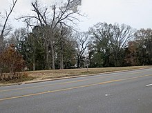 Un panneau au bord d'une route, parmi des arbres.
