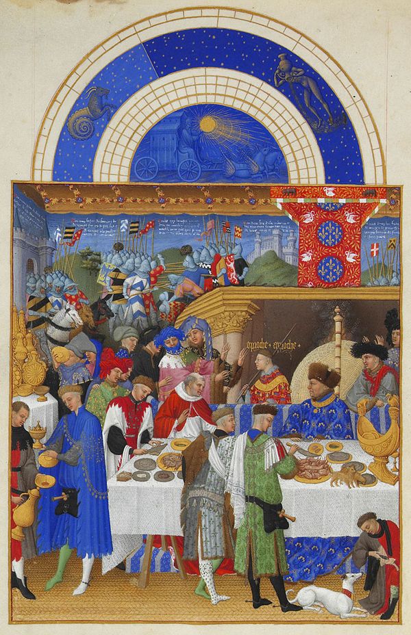 John, Duke of Berry enjoying a grand meal. The Duke is sitting with a cardinal at the high table, under a luxurious baldaquin, in front of the firepla