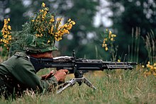 A camouflaged infantryman armed with an M60 machine gun.