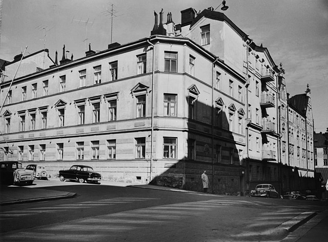 A black-and-white photograph of a three-storey apartment building.