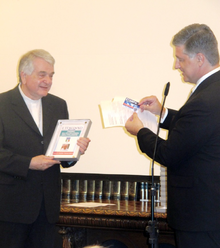 Marcelo Bomrad Casanova, editorial director of L'Italiano giving the prize awarded to Pope Francis to his Ambassador to Argentina Mons. Emil Paul Tscherrig Nunzio-apostolico.png