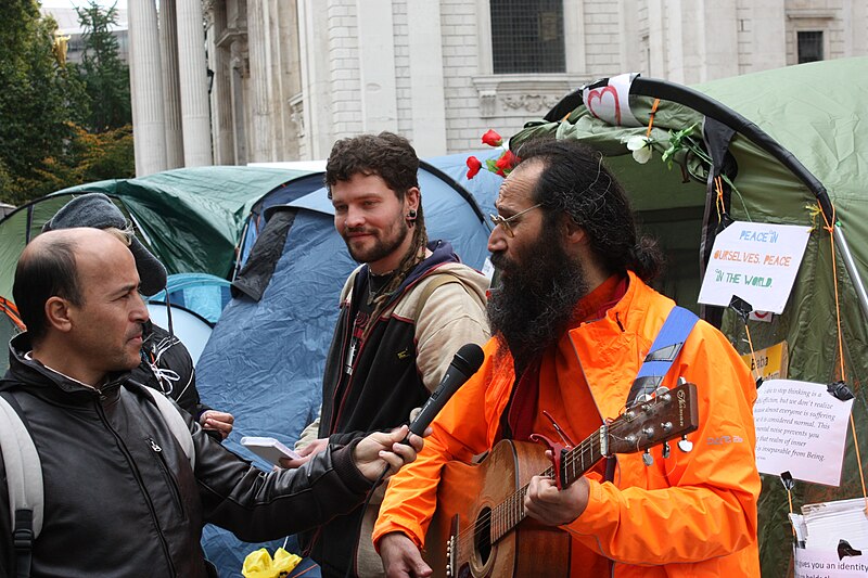 File:Occupy London - guitar player being interviewed.jpg