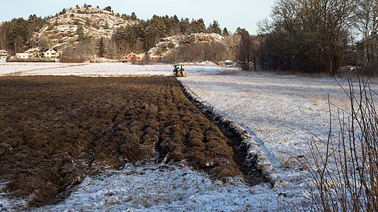 Half a plowed snowy field with a tractor, work suspended for lunch