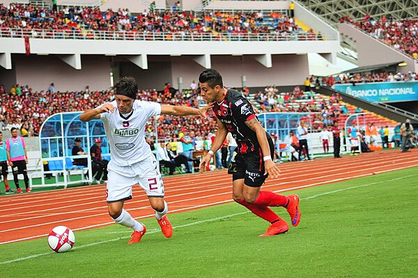 Saprissa's Christian Bolaños disputes the ball against Alajuelense's Rónald Matarrita. Alajuelense and Saprissa have the biggest rivalry in the league