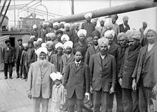 Sikhs aboard Komagata Maru, 1914. Gurdit Singh wearing light coloured suit, white beard, left foreground. Sikhs aboard Komagata Maru.jpg