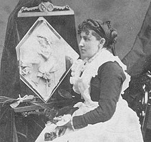 1877 г. Каролайн С. Брукс и нейната скулптура в масло по време на публична изложба в Amory Hall през 1877 г., от колекция от стереоскопични гледки на Робърт Н. Денис.jpg