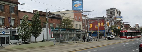 Stop layout: Signaled crossing (right), shelter, artwork along shelter roof, planter (left)