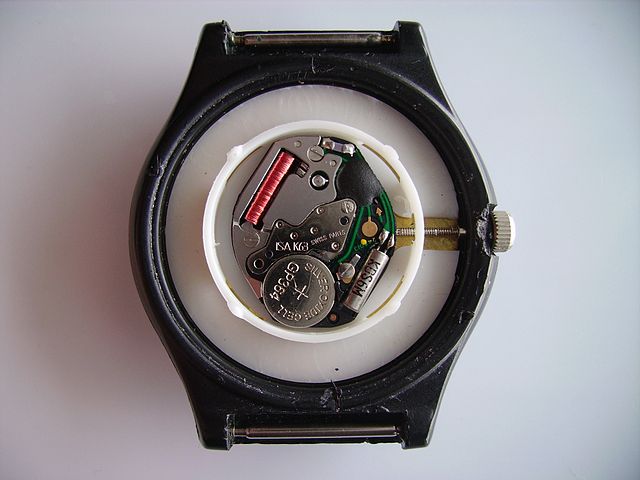 Basic quartz wristwatch movement. Bottom right: quartz crystal oscillator, left: button cell watch battery, top right: oscillator counter, digital fre