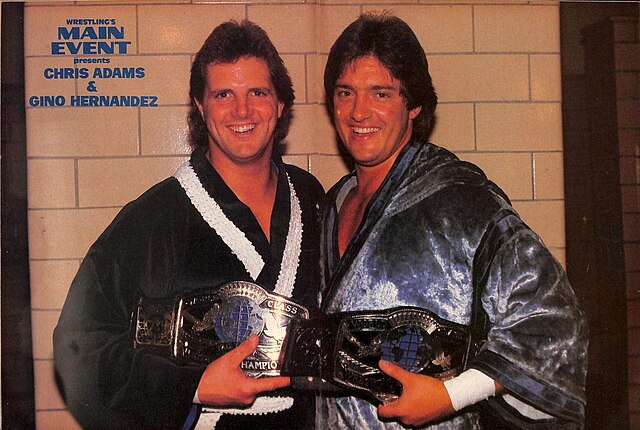 Adams with his tag team partner Gino Hernandez c. 1985. Known collectively as the "Dynamic Duo", the pair are seen here holding the WCWA World Tag Tea