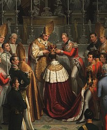 barevný obraz zachycující moment kdy arcibiskup Ankwicz společně s bývalým nejvyšším pourkrabím Kolovrat-Libštejnským vkládají korunu na hlavu Ferdinanda V., jsou obklopeni dalšími přítomnými osobami (rok 1836)