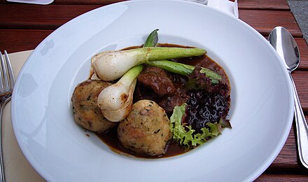 Venison goulash with dumplings, leeks, and lingonberry sauce served in Berlin