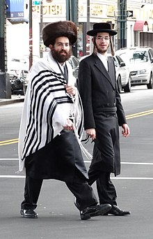 Hasidic men in Borough Park, Brooklyn. The man on the left is wearing a shtreimel and a tallit, and the other man traditional Hasidic garb: long suit, black hat, and gartel. Hasidic Men on Street.jpg