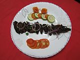 Homemade Beef Shashlik with tomato and lemon in white plate