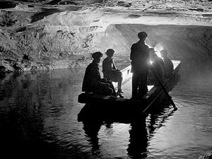 Several people in a jon boat on a river inside a cave.