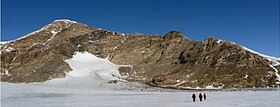 View to southeast of Mt. Luyendyk, a summit in the western Fosdick Mountains, Antarctica. Geologists are visible, approaching the base of the mountain. The summit is named for Bruce P. Luyendyk, professor (emeritus), University of California - Santa Barbara, in recognition of his contributions and discoveries in ground- and ocean-based Antarctic research, 1989-2015 Mt Luyendyk- Geologists Approach.jpg