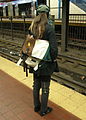 メッセンジャーバッグを斜めがけして背中側にし、電車で移動する女性。