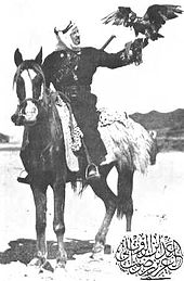 Hitam-dan-putih foto yang dipasang pria di atas kuda hitam. Elang bertengger di man uluran tangan.