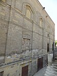 Exterior of the mosque. The old spaces for shops, now half-buried and below street level, are visible along the base.