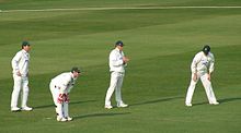 A wicket-keeper (bending down) and three slips wait for the next ball. The batter - out of shot - is a left-hander. Slips.jpg