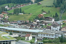 Lauterbrunnen station seen from the east. Wengernalpbahn trains can be seen in the nearest platforms under the glass roof. The terminus of the cable car stage of the Bergbahn Lauterbrunnen-Murren can be seen to the right. WAB Bahnhof Lauterbrunnen 1.jpg