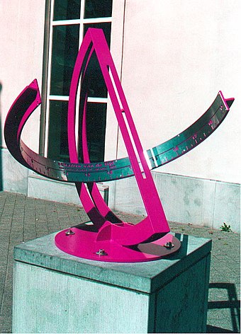 Equatorial bow sundial in Hasselt, Flanders in Belgium 50°55′47″N 5°20′31″E﻿ / ﻿50.92972°N 5.34194°E﻿ / 50.92972; 5.34194﻿ (Hasselt equatorial bow sundial).  The rays pass through the narrow slot, forming a uniformly rotating sheet of light that falls on the circular bow.  The hour-lines are equally spaced; in this image, the local solar time is roughly 15:00 hours (3 p.m.). On September 10, a small ball, welded into the slot casts a shadow on centre of the hour band.