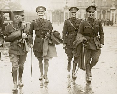 a group of four males in uniform walking along a street