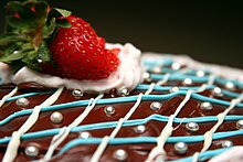 A chocolate cake decorated with icing, strawberries, and silvery sugar beads or Dragées