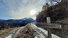 Rètol de fusta en una pista forestal, que indica el camí cap a les localitats de Serveto i Sin. El rètol està escrit en aragonès gistaví, i s'hi llegeix: "Pista ta Serveto y Sin".