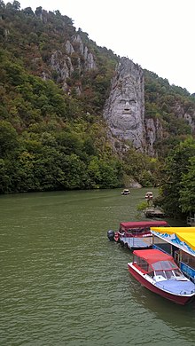 Sculpture monumentale à même la roche, en bord de rivière.