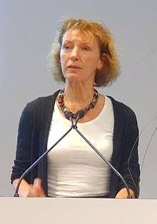 A woman stands at a microphone.