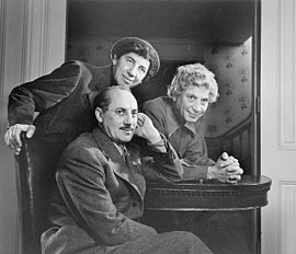 Harpo Marx, à droéte; À gueuche, Chico Marx ; assis, Groucho Marx.