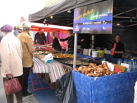 Street food including fried vendace at a market in Turku, in the front traditional wooden mugs for sale (as souvenirs)