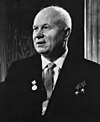 An elderly man in a suit, with three medals pinned on it