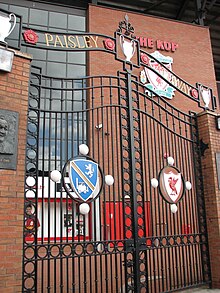 A set of gates with the inscription «Paisley Gateway» at the top. In the middle of the sets of gates are two emblems