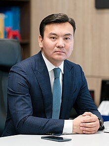 Headshot of Rauan Kenzhekhanuly in an office. He is a middle-aged man wearing a morning suit.