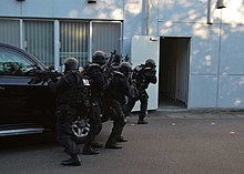 Japanese prefectural police Special Assault Team members preparing to enter a building SAT operators rushing into a building.jpg