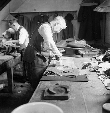 A tailor pressing a pair of trousers in the workroom of Henry Poole & Co in 1944