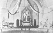 Interior of church, with altar and sanctuary rail, and fabric bands in red and white hanging from the ceiling