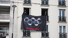 Protest action in Paris, April 2008, displaying a 'Reporters Without Borders (RSF)' flag depicting the Olympic rings in the form of handcuffs or padlocks, along with the legend 'Beijing 2008' Torch relay press freedom.jpg