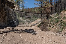 A heavy gauge metal barrier protects Forest Road 263 and the canyon west of Montezuma, New Mexico, added as a method of flood and debris control following the fire. A heavy gauge metal barrier protects Forest Road 263 and the canyon west of Montezuma, New Mexico.jpg